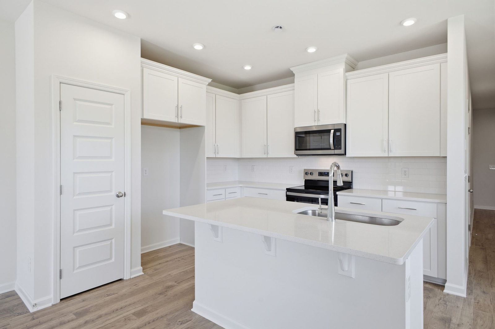 kitchen with white cabinets and counters, wood floors, and stainless steel appliances
