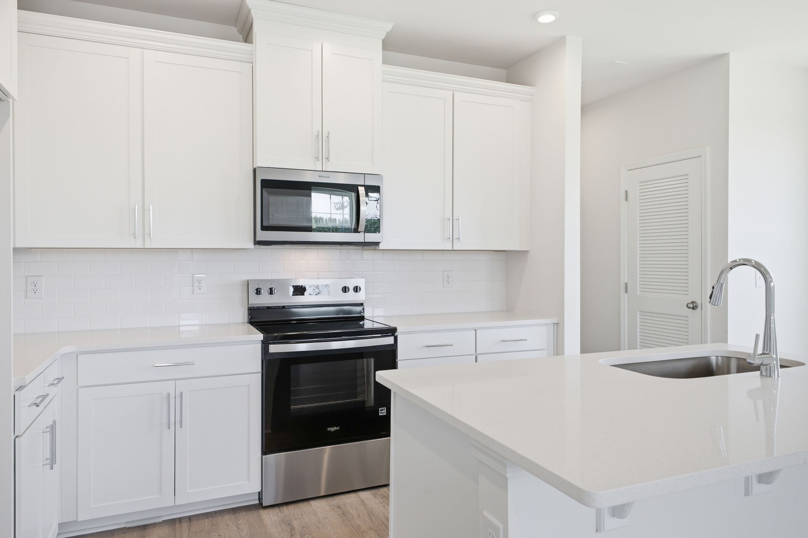 kitchen with white cabinets and counters, wood floors, and stainless steel appliances
