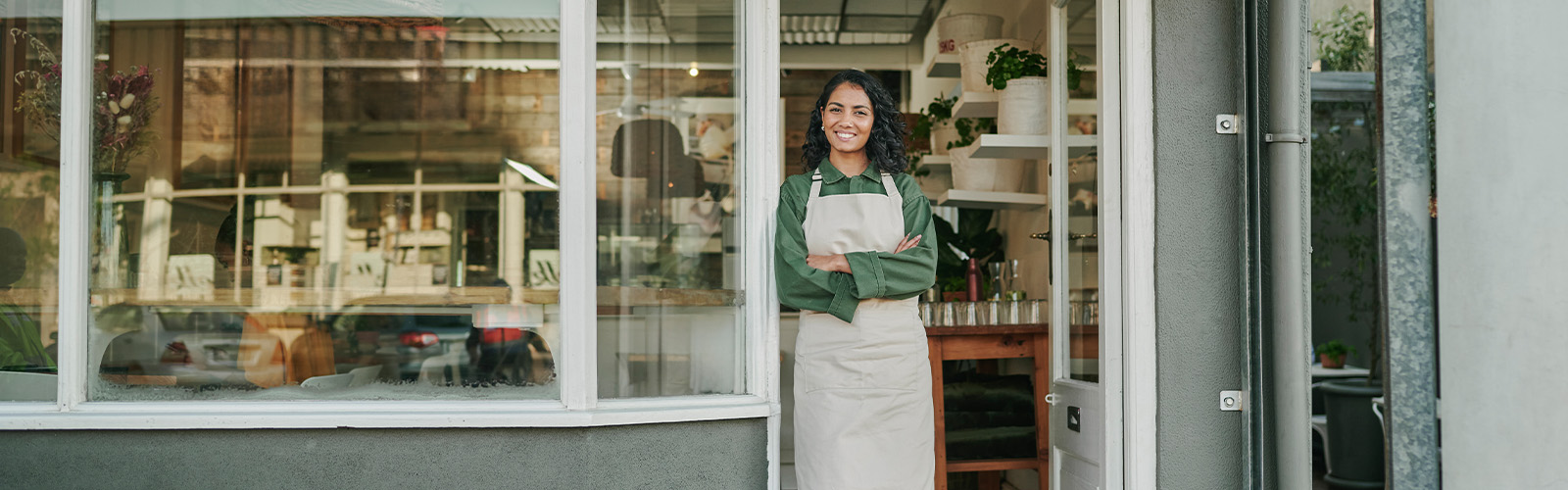 A smiling woman standing in front of her store