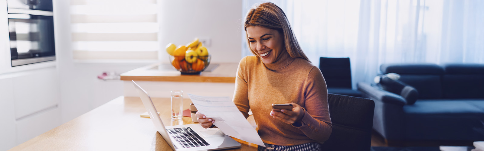 A woman looking at her cell phone and laptop