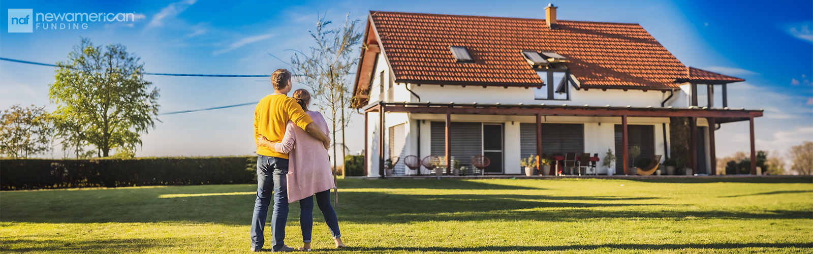 A couple embracing and staring at an older home in the distance.