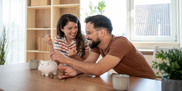 Young couple putting money in a piggy bank