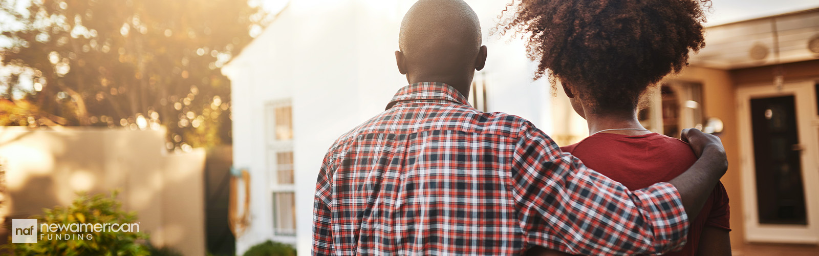 A straight, Black couple with their backs to the camera look at a home.