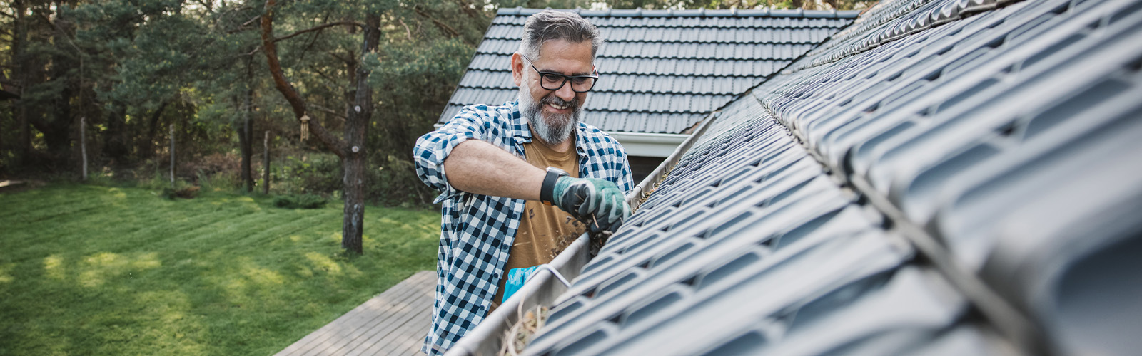 Homeowner cleaning leaves out of their gutter