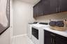 laundry room with neutral floors and dark cabinets
