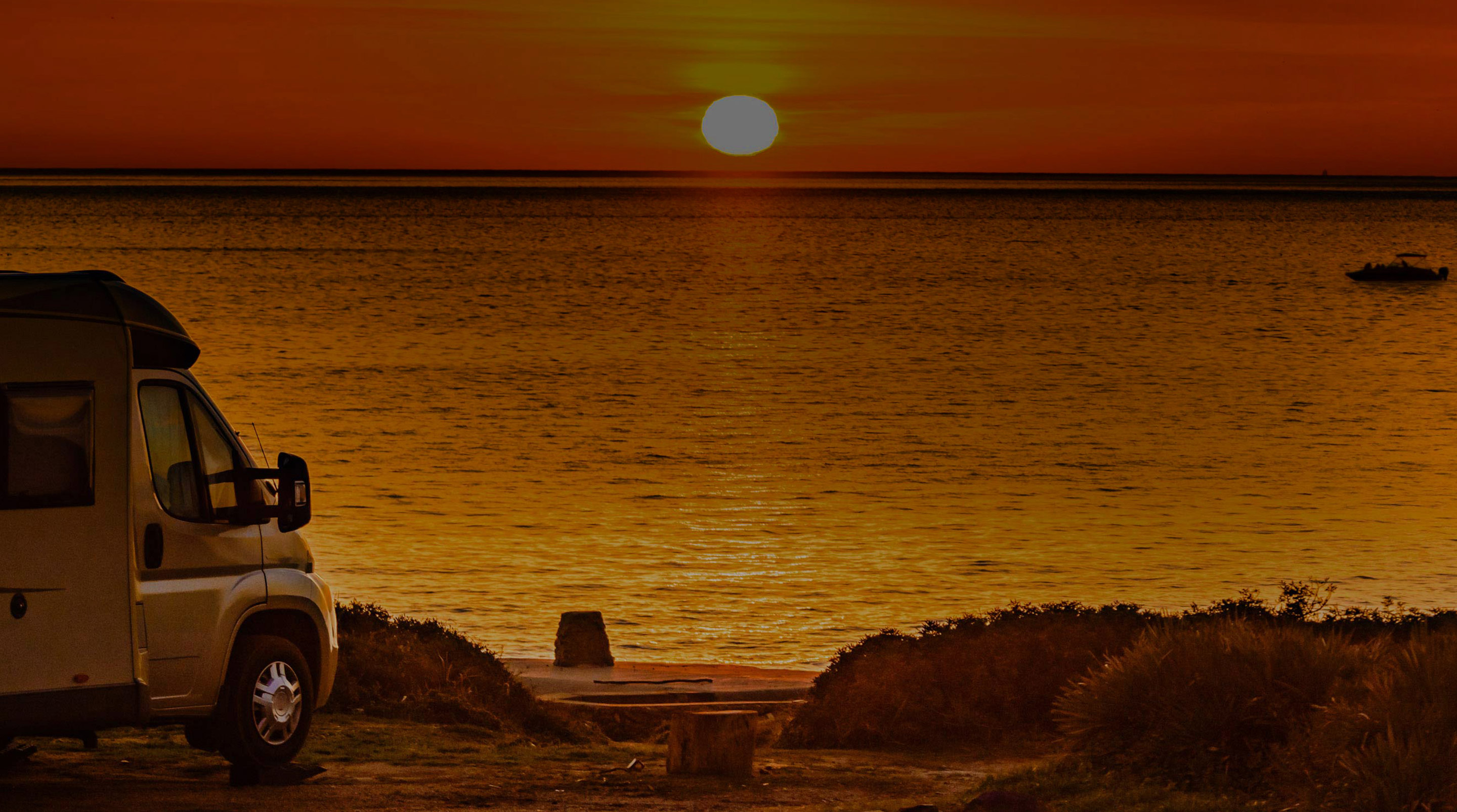 RV with onboard Fathom e-power system faces golden sunset on cliff above beach