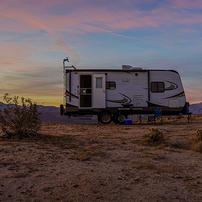 RV with onboard Fathom e-power system trailer in desert at sunset