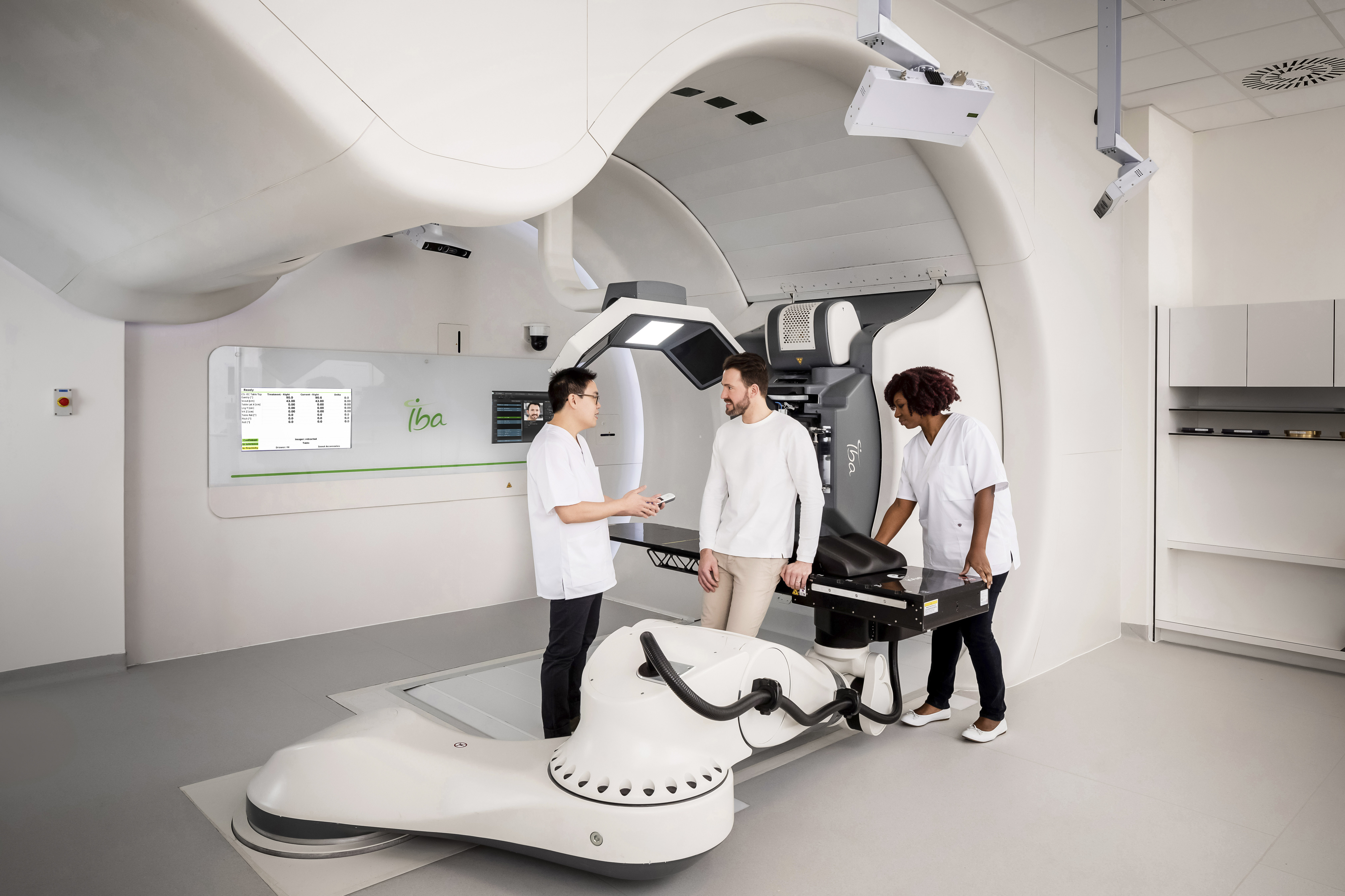 Proteus ONE proton therapy machine and two technicians speaking with a patient.