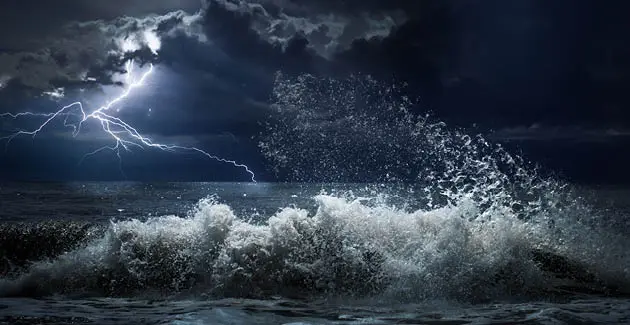 A photo of a storm, lightning over the sea with waves breaking and crashing