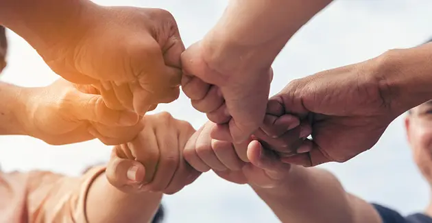 Close-up of several hands coming together for a group fist bump, symbolizing unity and teamwork
