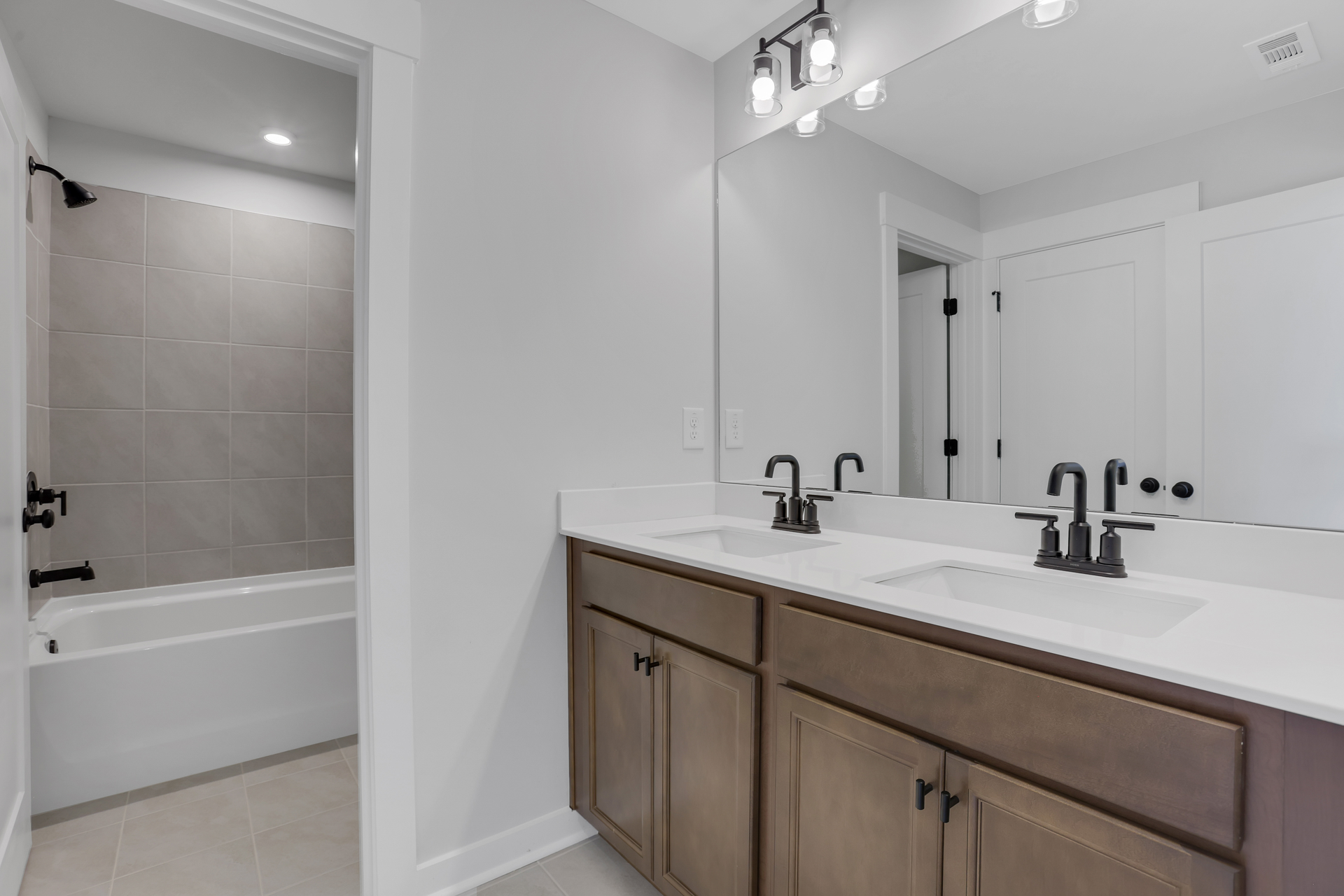 secondary bathroom with wood cabinets and tile flooring