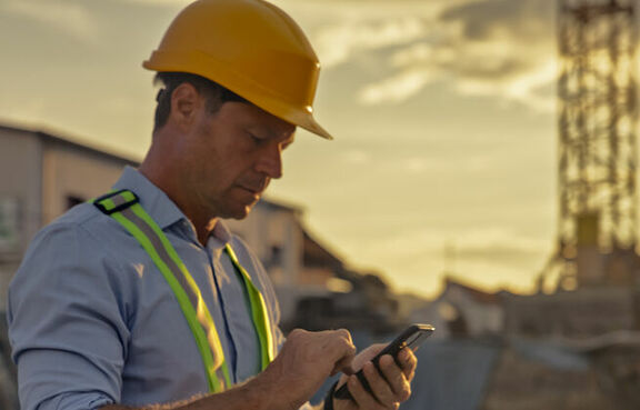 Male construction worker checking smartphone at site during golden