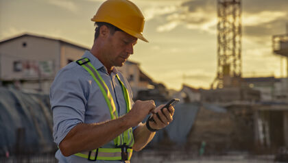 Male construction worker checking smartphone at site during golden