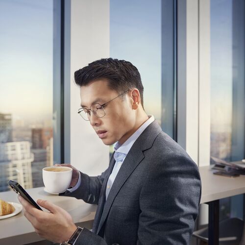 一位西裝革履的男士在一家商務咖啡館戴著 HOYA MySelf Profile 眼鏡