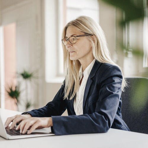 Mujer trabajando en una computadora portátil con gafas ocupacionales