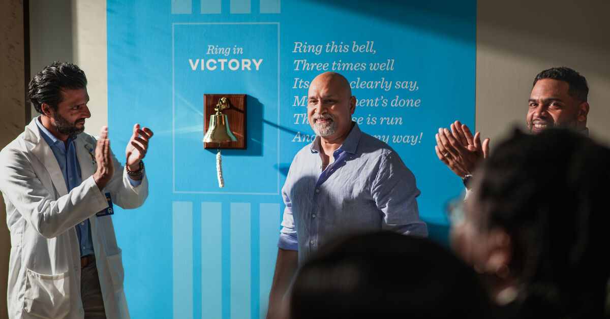 Dr. Parikh claps his hands after patient rings the victory bell