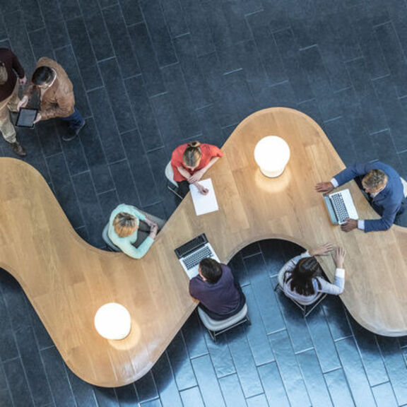 Birds eye view of business people collaborating at modern desk