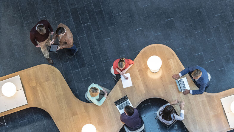 Birds eye view of business people collaborating at modern desk