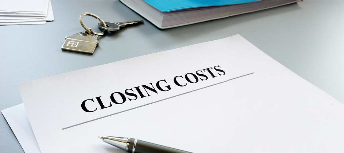A piece of paper with closing costs written on it and a pen on top of it.
