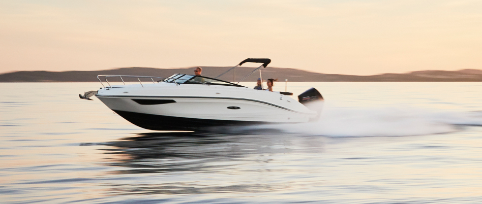 Black and white powerboat accelerates across the sea beneath a summery sky