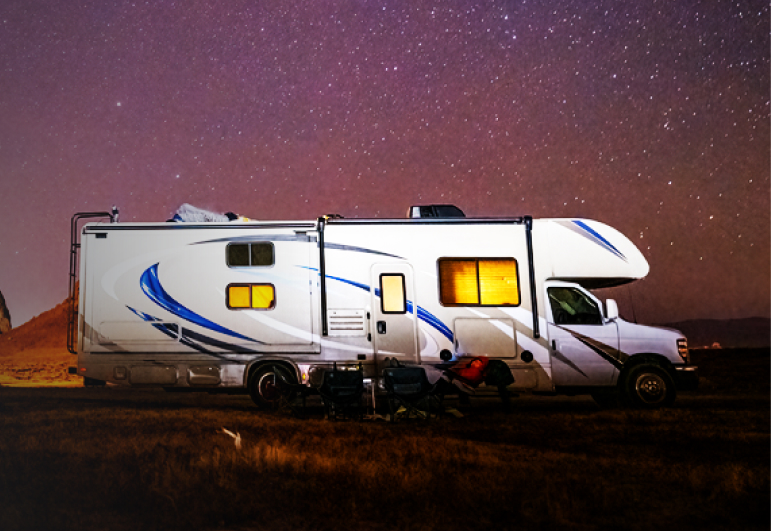 Floodlit arge RV with onboard Fathom e-power system on a prairie beneath a starry night sky