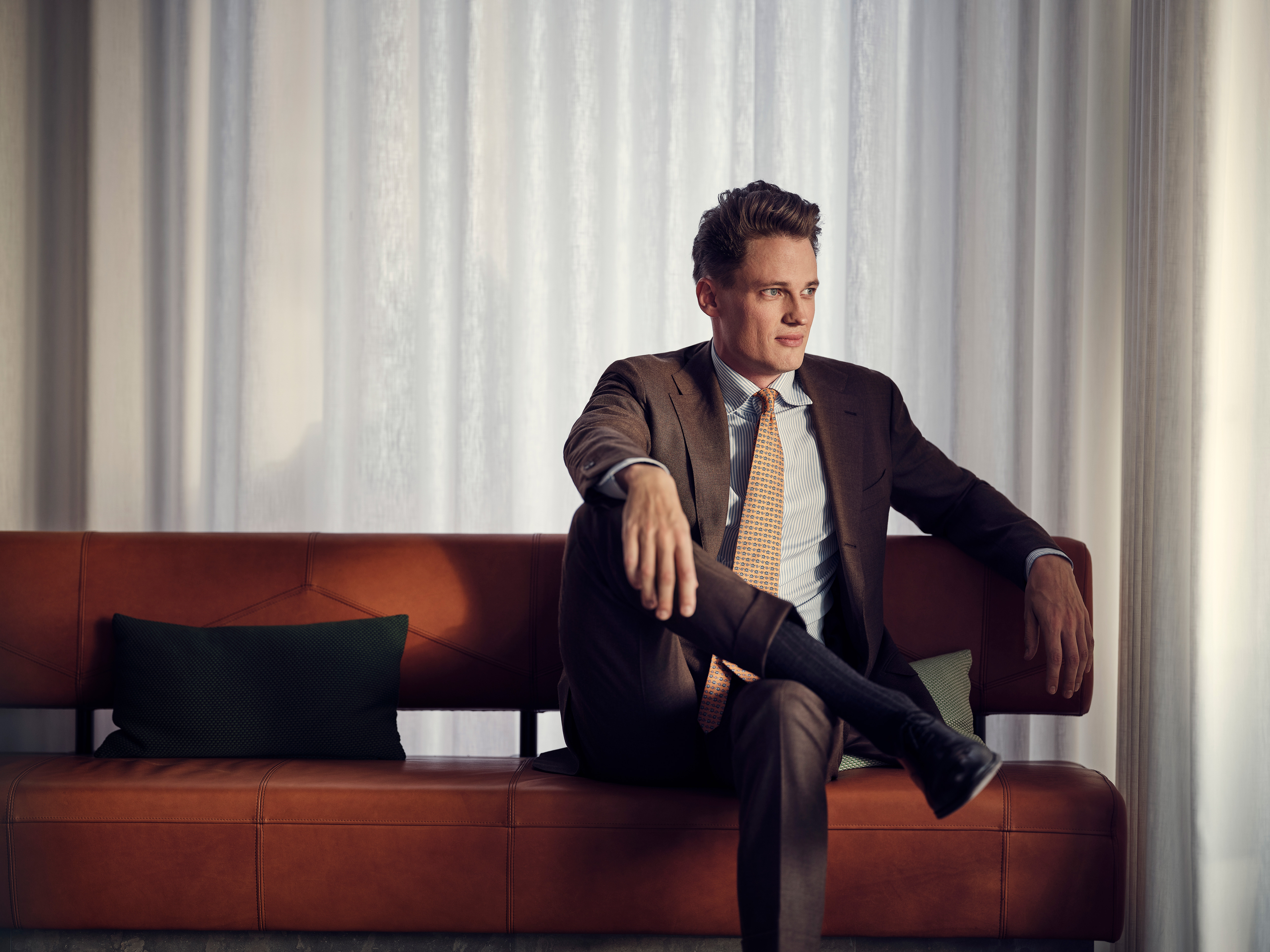 Mann im Anzug sitzt auf Ledersofa