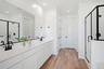 spacious bedroom with white cabinets, a double sink, and black hardware