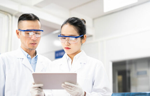 Two scientists in a laboratory looking at a tablet 