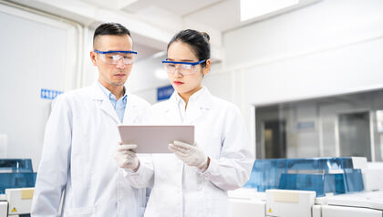 Two scientists in a laboratory looking at a tablet 
