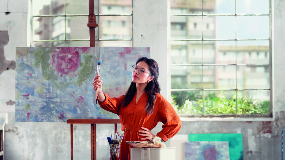 Female artist looking at paintbrush while wearing HOYA Sensity Shine lenses