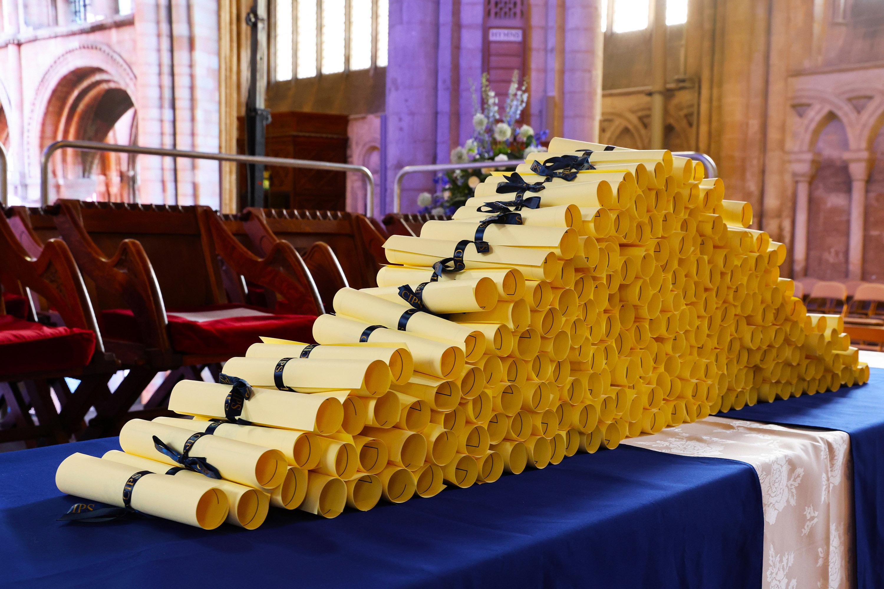 Stacked diplomas tied with blue ribbons on a table