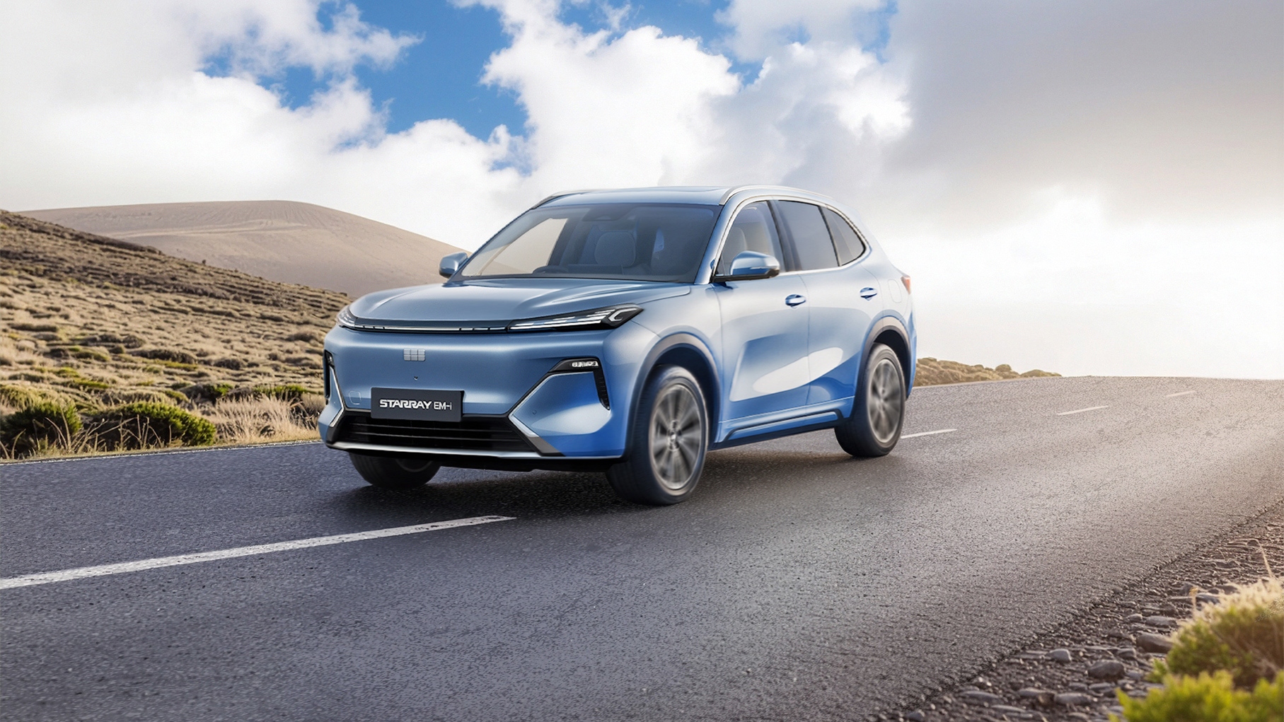 Light blue Geely Starray driving along an open road through a hilly landscape under a bright sky with scattered clouds. The vehicle is shown in three quarter front view, with motion blur on the wheels and road surface to suggest movement.