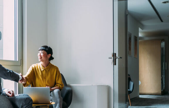 two business professionals shaking hands in a small meeting room