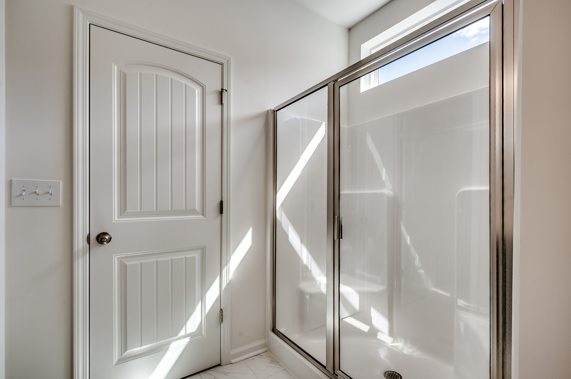 spacious walk-in shower with tan walls and tile flooring
