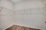 spacious walk-in closet with white wire shelving and hardwood flooring