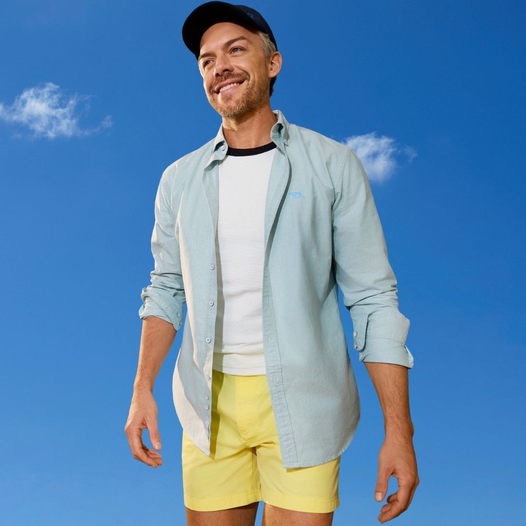 An image of a smiling man wearing a cap and dressed for spring.