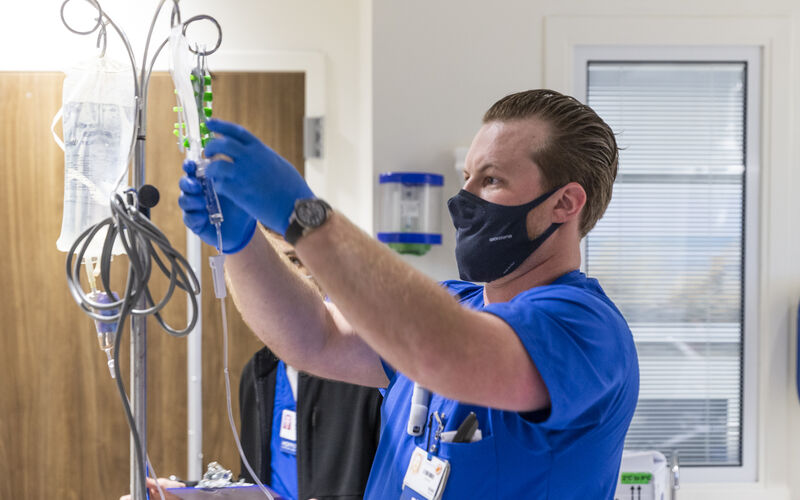 Nurse Ivan Ross hangs a bag of cells to begin a TIL infusion.