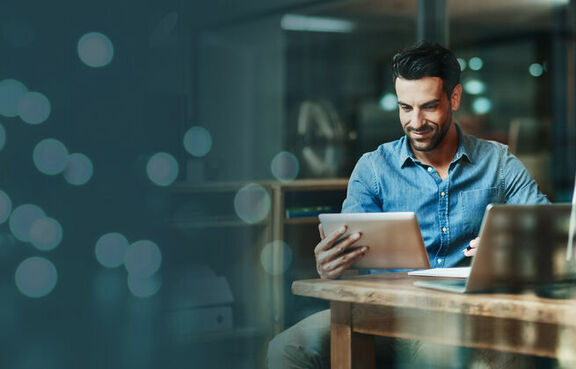 Man at desk looking at a tablet