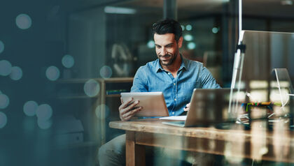 Man at desk looking at a tablet