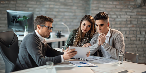 A couple sitting at a desk looks at paperwork with a professional.