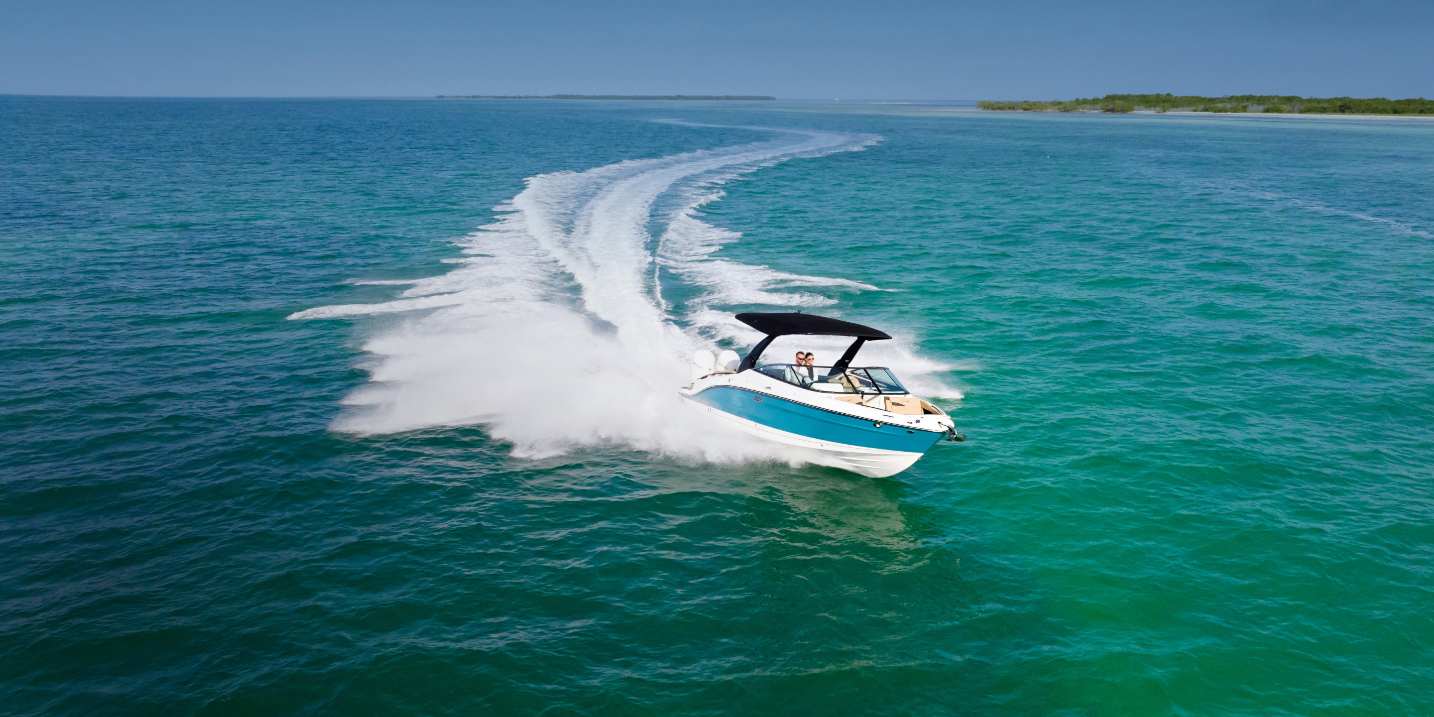 Couple speeding along the coast in a powerboat fitted with Lenco trim tabs