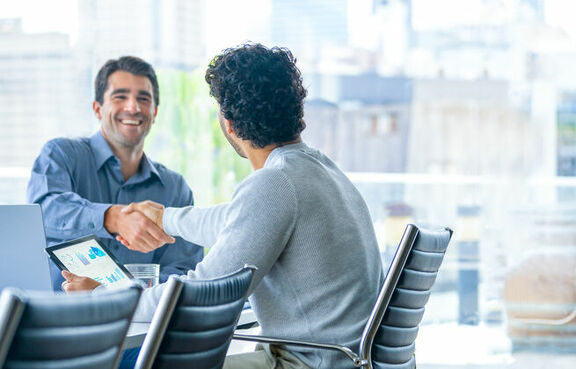 Two businessmen shaking hands over a conference table