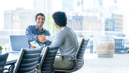 Two businessmen shaking hands over a conference table