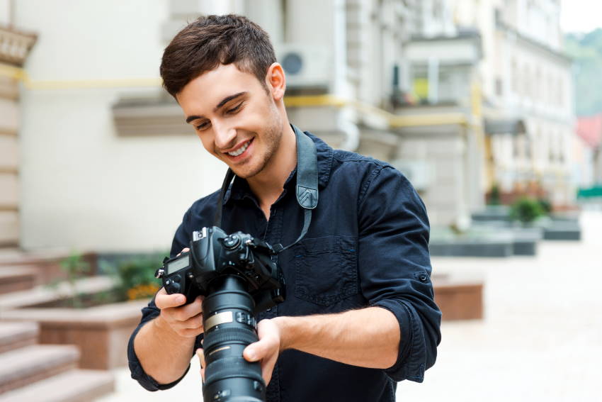 Mlad moški se ukvarja s fotografijo in ima med fotografiranjem oddih za ogled narajenih fotografij.