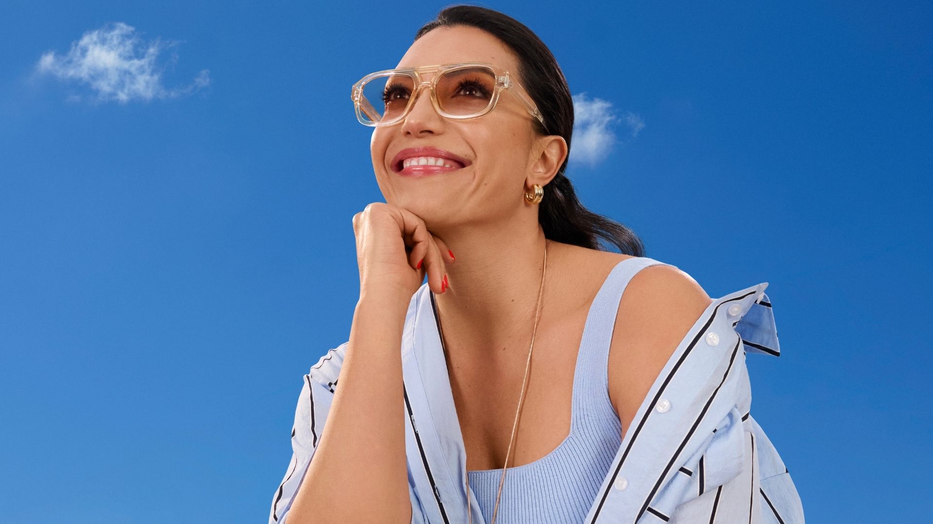 Image of a woman smiling, wearing sunglasses and dressed for spring.