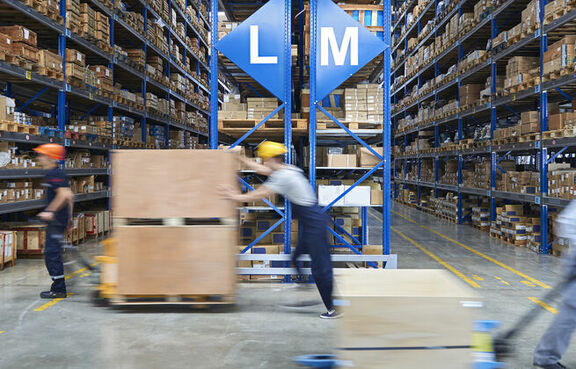 Workers pulling pallets of boxes through a warehouse