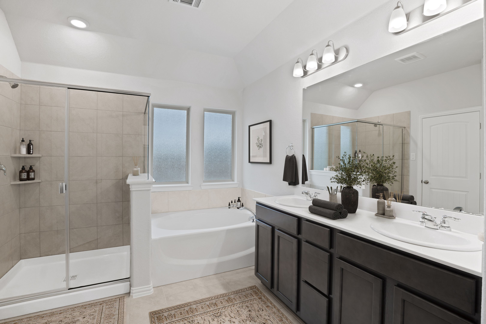 primary bathroom with double sink vanity, glass walk-in shower, and a large soaking tub