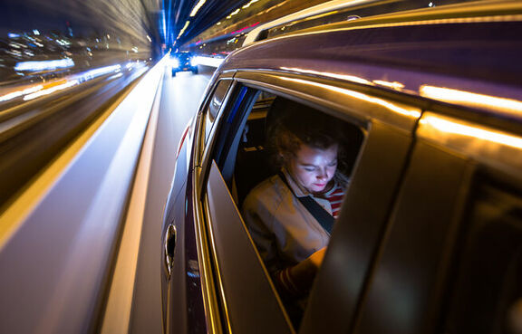 Woman in the back of a car looking at a phone