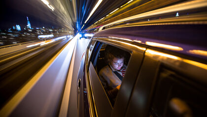 Woman in the back of a car looking at a phone
