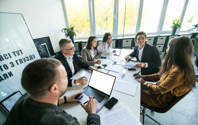 Group of young professionals working at a long table in a conference room